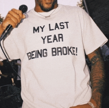 a man holding a microphone wearing a shirt that says my last year being broke