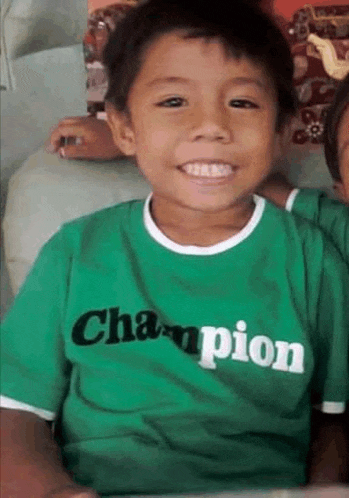 a young boy wearing a green champion shirt is smiling