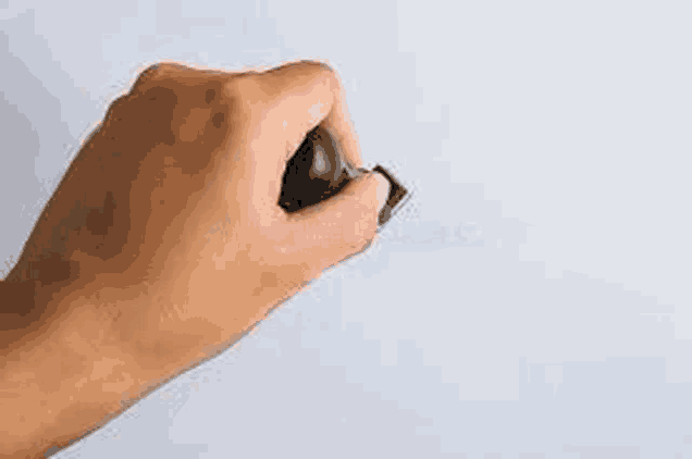 a close up of a person 's hand holding a black marker on a white board .