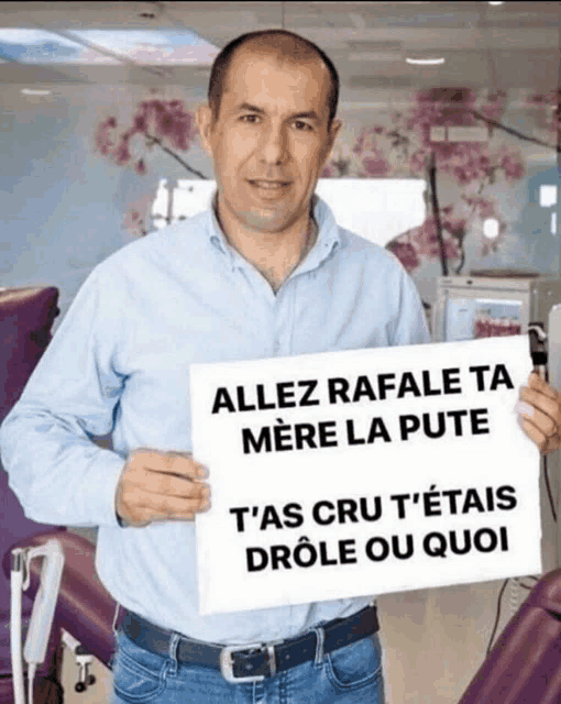 a man in a blue shirt holds up a sign that says allez rafale ta mere la pute