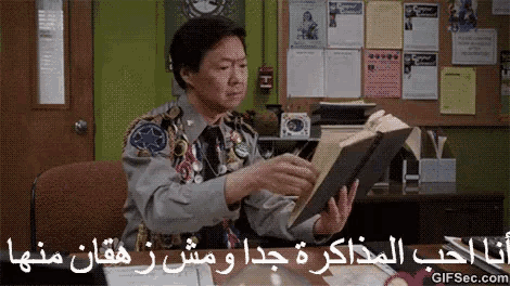 a man in a scout uniform is reading a book in a foreign language .