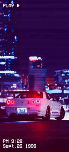 a white nissan skyline r34 is driving down a street at night .