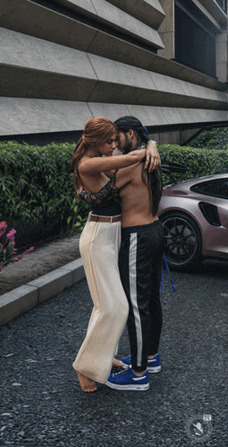 a man and woman hugging in front of a pink car