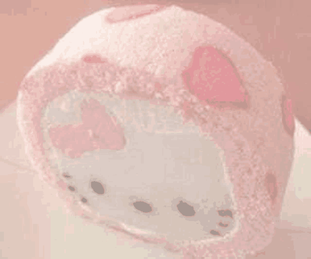 a pink and white hello kitty cake roll with hearts on it .