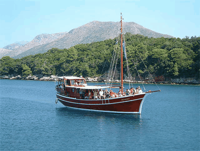 a boat in the water with a mountain in the background and a few people on the boat