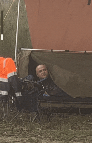 a man is laying in a tent with his head sticking out of it