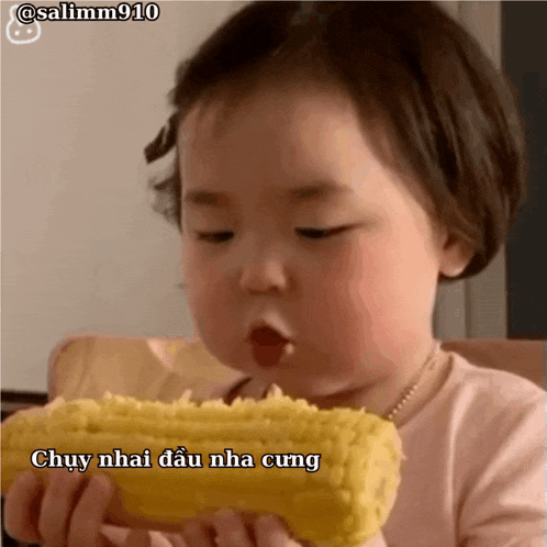 a baby is eating corn on the cob with a foreign language caption