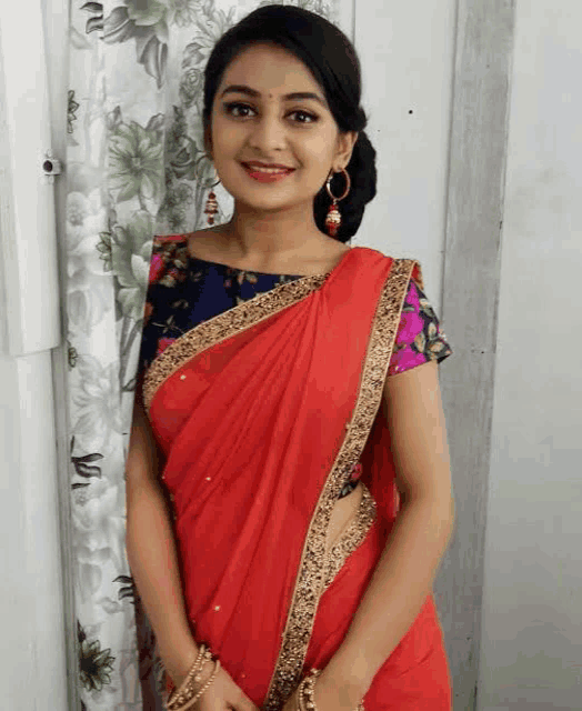 a woman in a red saree and a blue blouse is smiling .