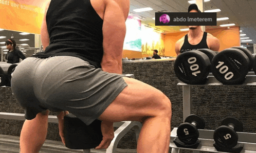 a man squatting in front of dumbbells with abdo imeterem in the corner