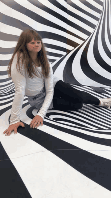 a girl sitting on a black and white striped floor