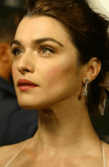 a close up of a woman 's face with a flower in her hair and earrings