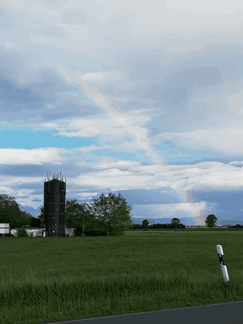 a rainbow is visible over a field with a tower in the background