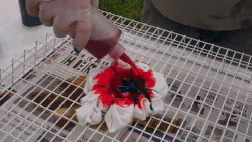 a person is pouring red and blue dye on a piece of cloth with a newspaper in the background that says ' hier '