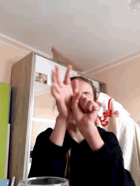 a woman making a funny face with her hands in front of a mirror