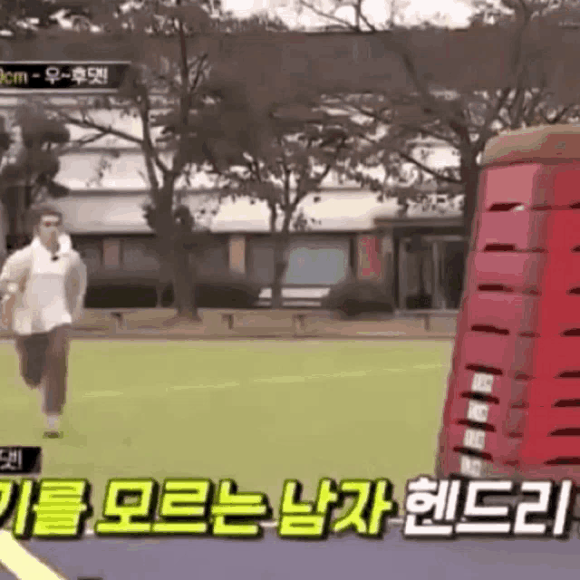 a man is running on a track next to a red stack of boxes .