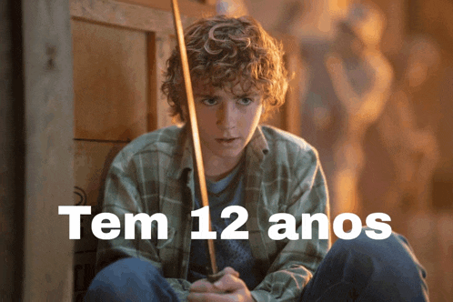 a young boy with curly hair is holding a sword and the words tem 12 anos are above him