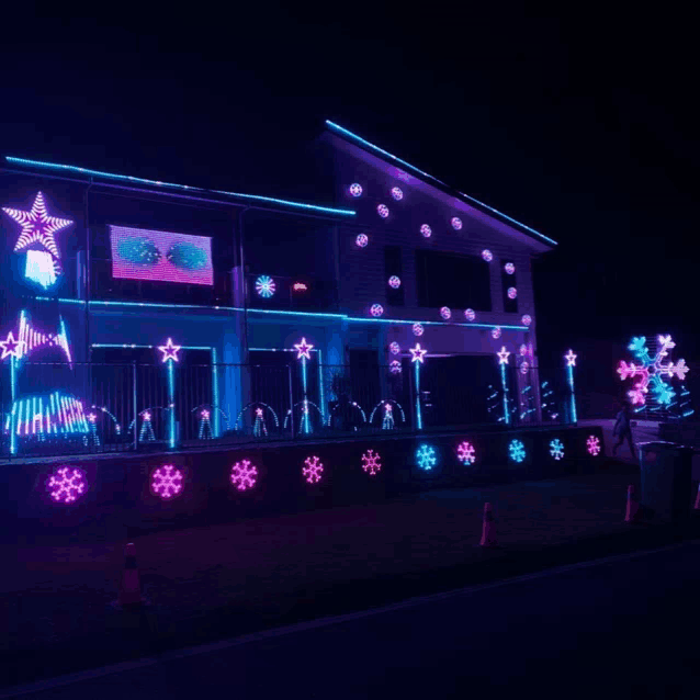 a house decorated with christmas lights and snowflakes at night