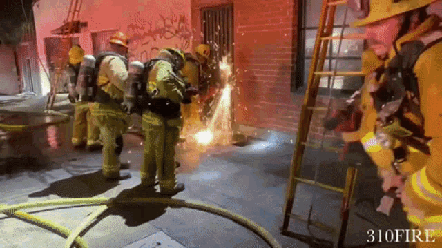 a group of firefighters are standing in front of a brick building with the number 310 fire written on the bottom