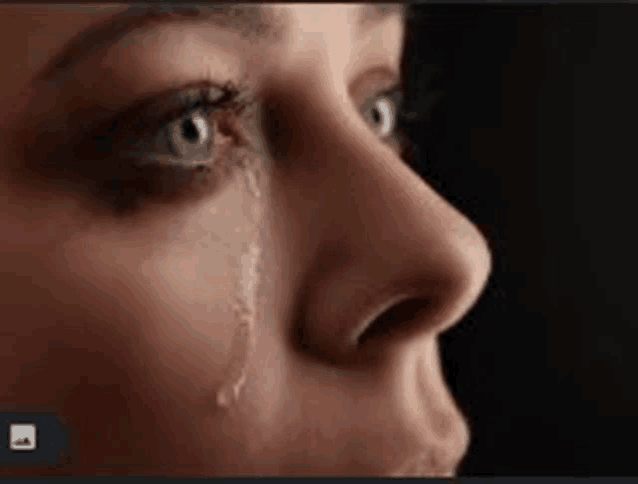 a close up of a woman 's face with a tear running down her face .