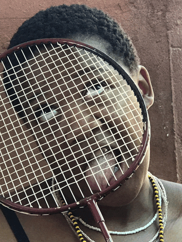 a woman holds a badminton racquet in front of her face