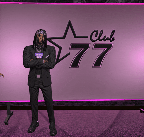 a man in a black suit stands in front of a club 77 sign