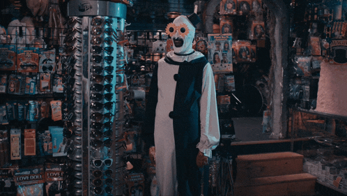 a clown in a black and white costume stands in front of a love doll display