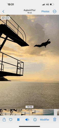 a phone screen shows a picture of a man jumping into the ocean