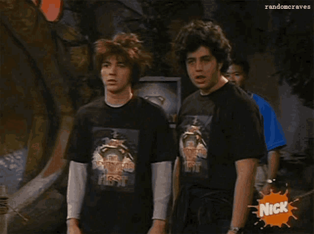 two boys wearing black shirts that say the dinosaur fest stand in front of a dinosaur