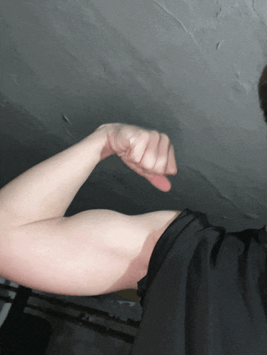 a man in a black shirt is flexing his biceps