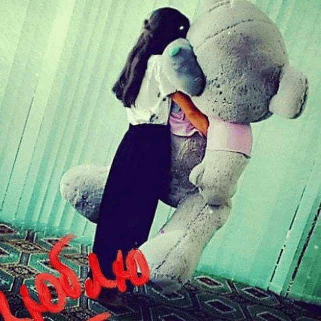 a woman is holding a giant teddy bear in her arms .