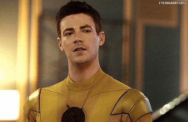 a close up of a man in a yellow superhero costume looking at the camera .