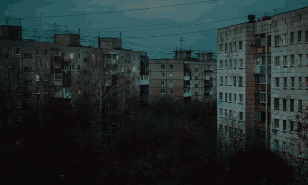 a row of apartment buildings with the lights on