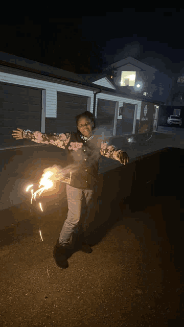 a girl is holding a sparkler in front of a garage door