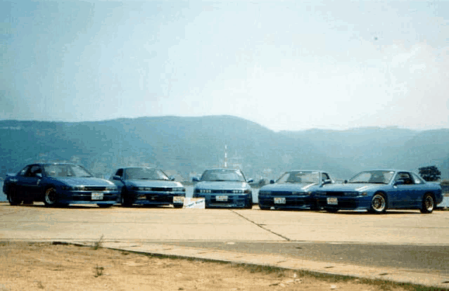 four blue cars are parked next to each other on a runway