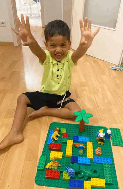 a young boy is sitting on the floor playing with lego