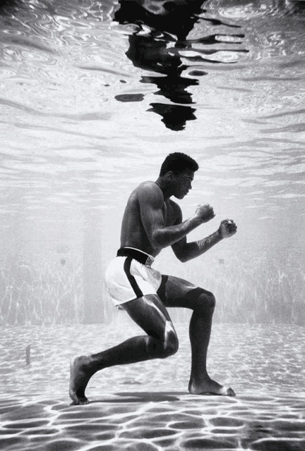 a man in boxing shorts is kneeling underwater