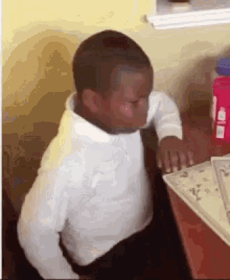 a young boy is sitting at a table with his eyes closed and a water bottle in the background .