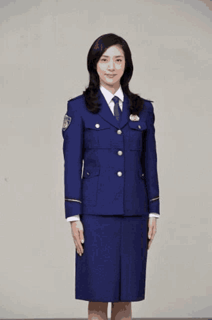 a woman in a police uniform is standing in front of a wall .