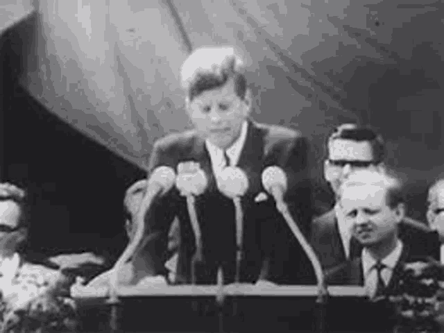 a black and white photo of a man standing at a podium giving a speech .