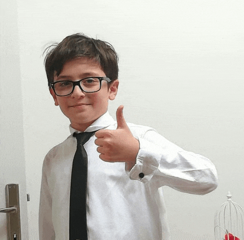 a young boy wearing glasses and a black tie is giving a thumbs up