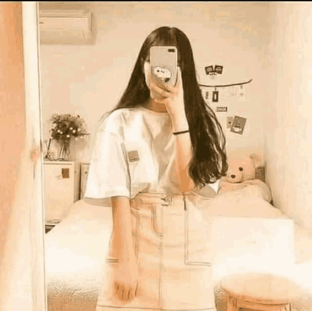 a girl is taking a selfie in front of a mirror in her bedroom .