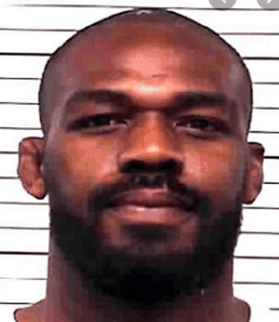 a close up of a man 's face with a beard and a police line behind him .