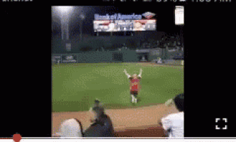 a man stands on a baseball field with his arms in the air in front of a banner that says bank of america