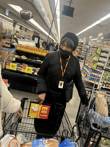 a woman wearing a mask pushes a shopping cart in a supermarket