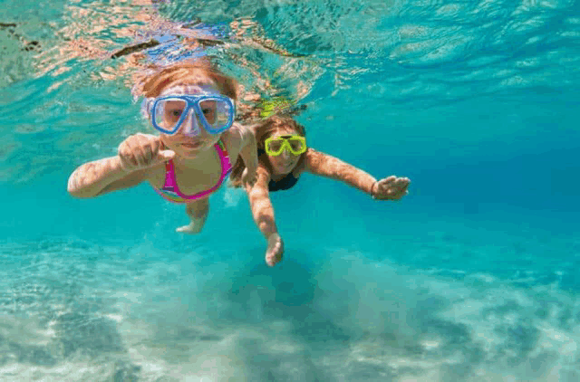 a woman and child are swimming underwater in the ocean .