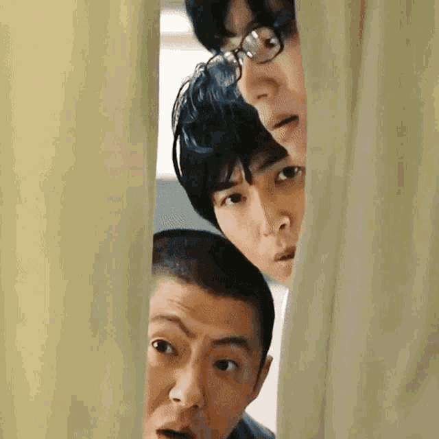 three men are peeking out from behind a curtain and looking at something .