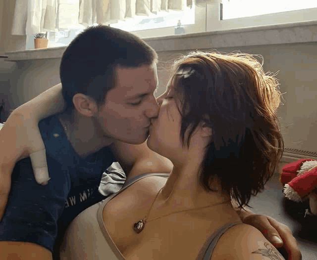 a man kissing a woman who is wearing a tank top that says ew