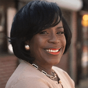 a woman wearing a sweater and a necklace is smiling