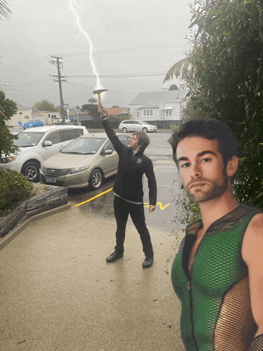 a man in a green tank top holds up a hammer in front of a lightning bolt