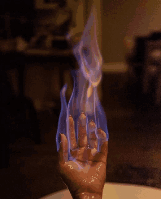 a person 's hand is on fire with a blue flame